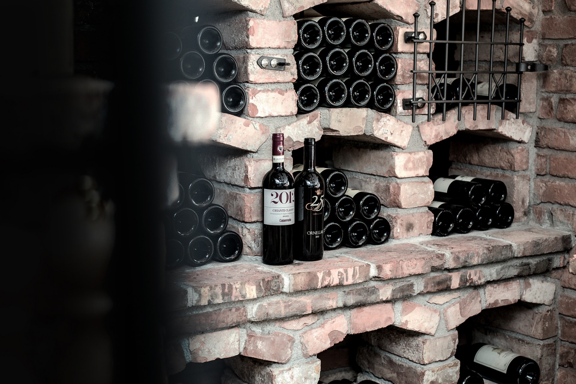 A rustic brick wine cellar with bottles neatly organized in built-in racks and a few select bottles showcased at the forefront.