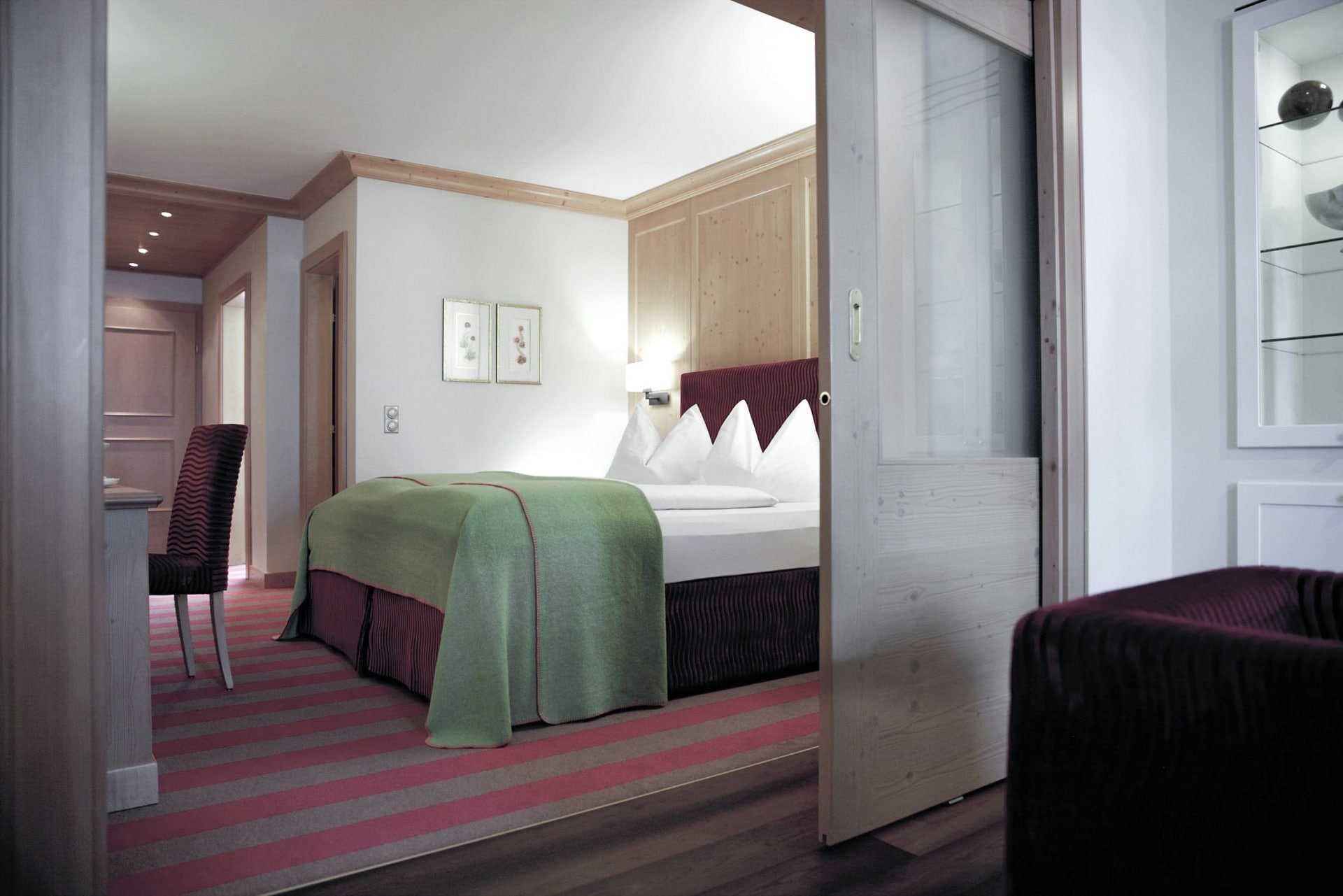 Ein modernes und gemütliches Hotelzimmer mit einem ordentlich gemachten Bett, warmer Beleuchtung und einer geschmackvollen Mischung aus Holzakzenten und zeitgenössischem Design.