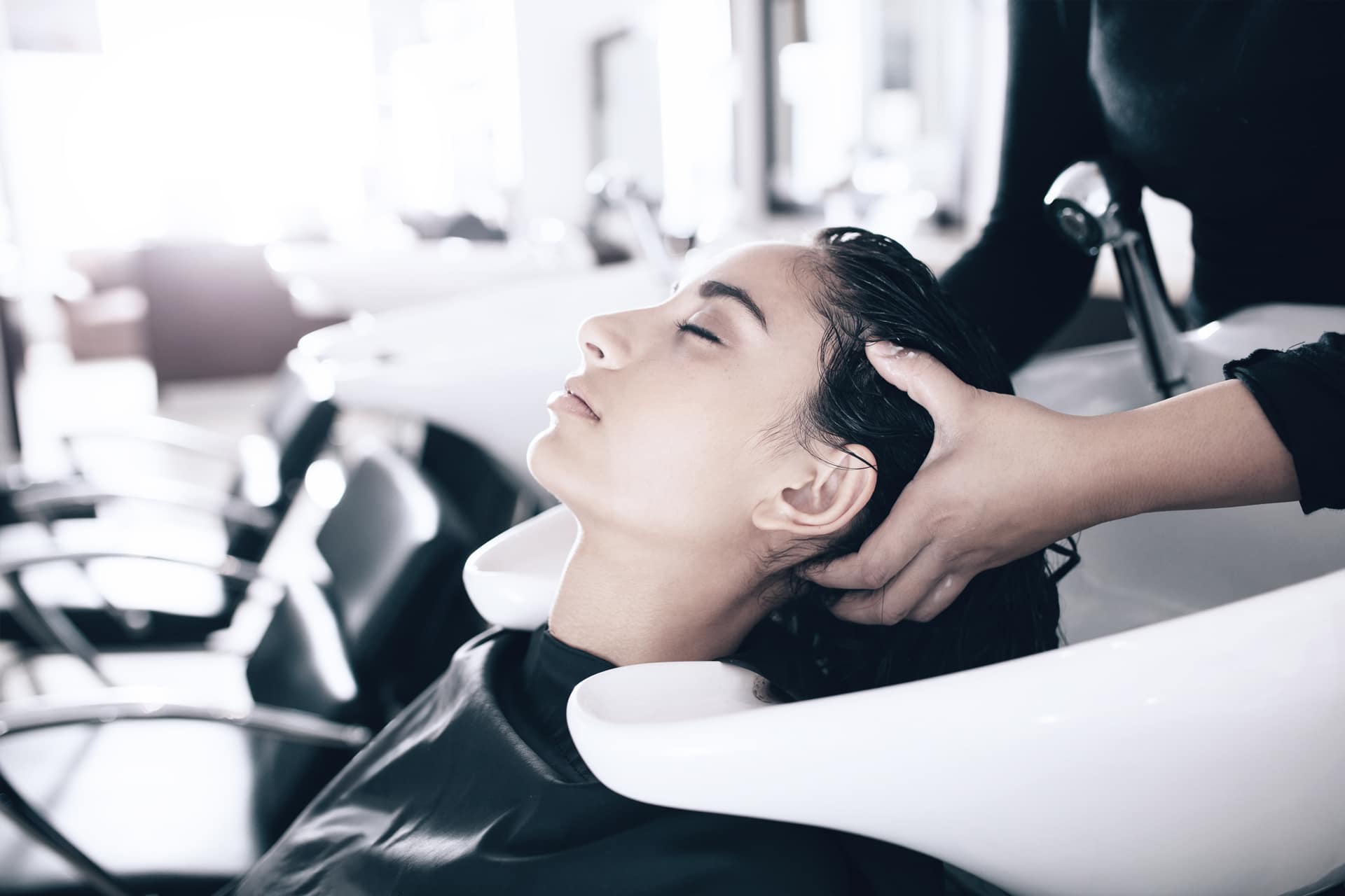 Eine Frau entspannt sich beim Haarewaschen in einem Salon und erlebt einen Moment der Ruhe während ihrer Verwöhnsitzung.