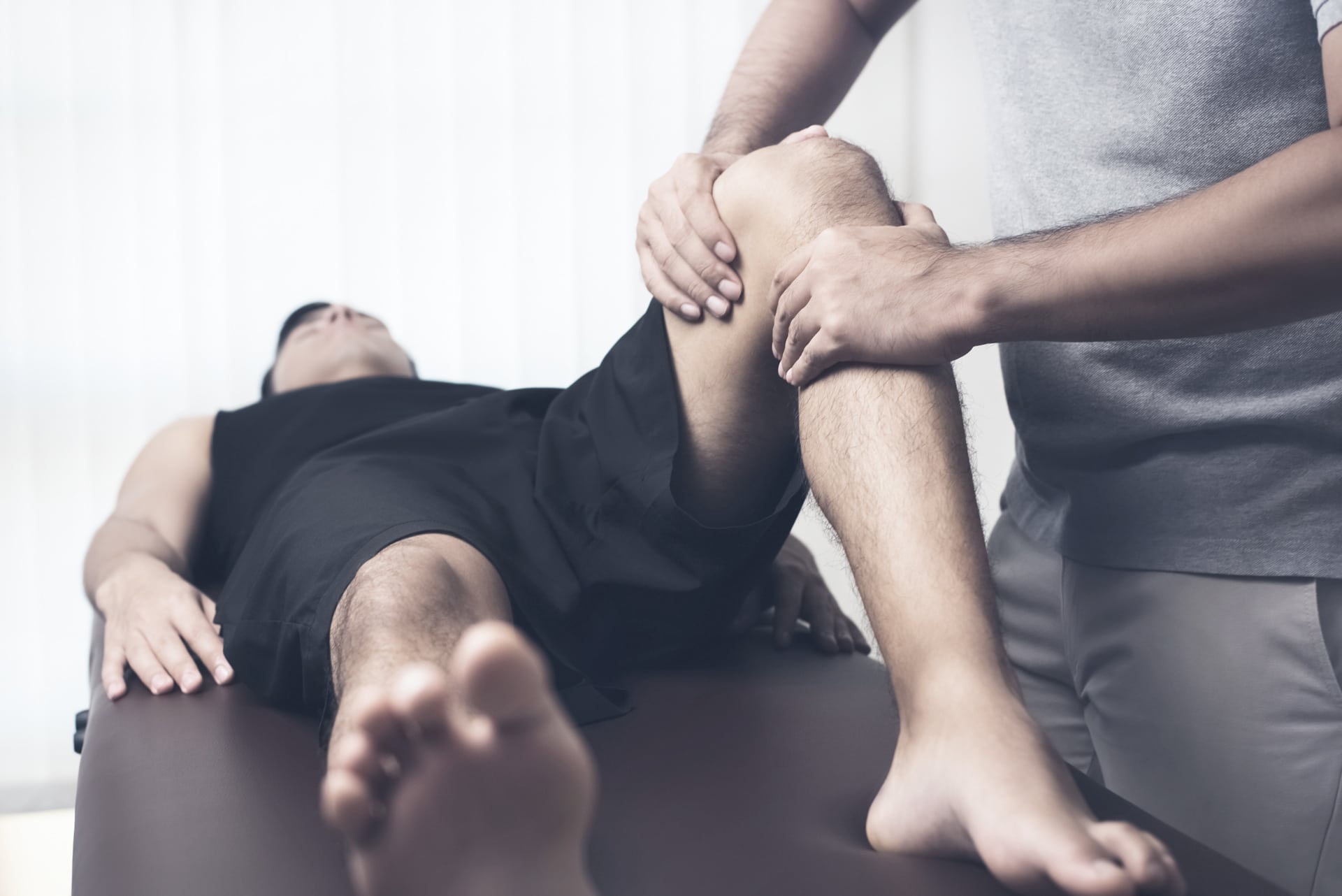 Physiotherapeut macht mit einem Patienten Übungen zur Knierehabilitation.