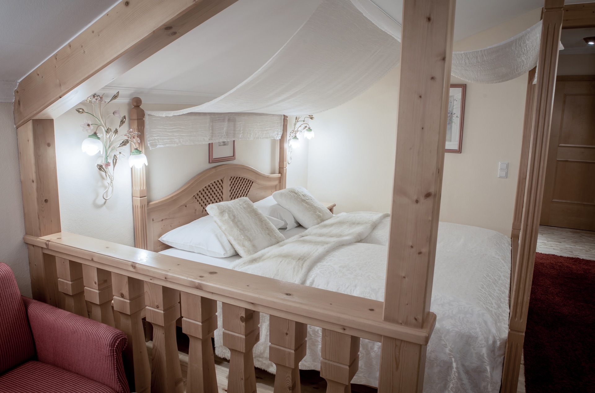 A cozy and inviting bedroom featuring a rustic wooden four-poster bed draped with sheer curtains, complete with plush pillows and a soft comforter, all bathed in warm ambient lighting, creating a snug and peaceful sleeping nook.